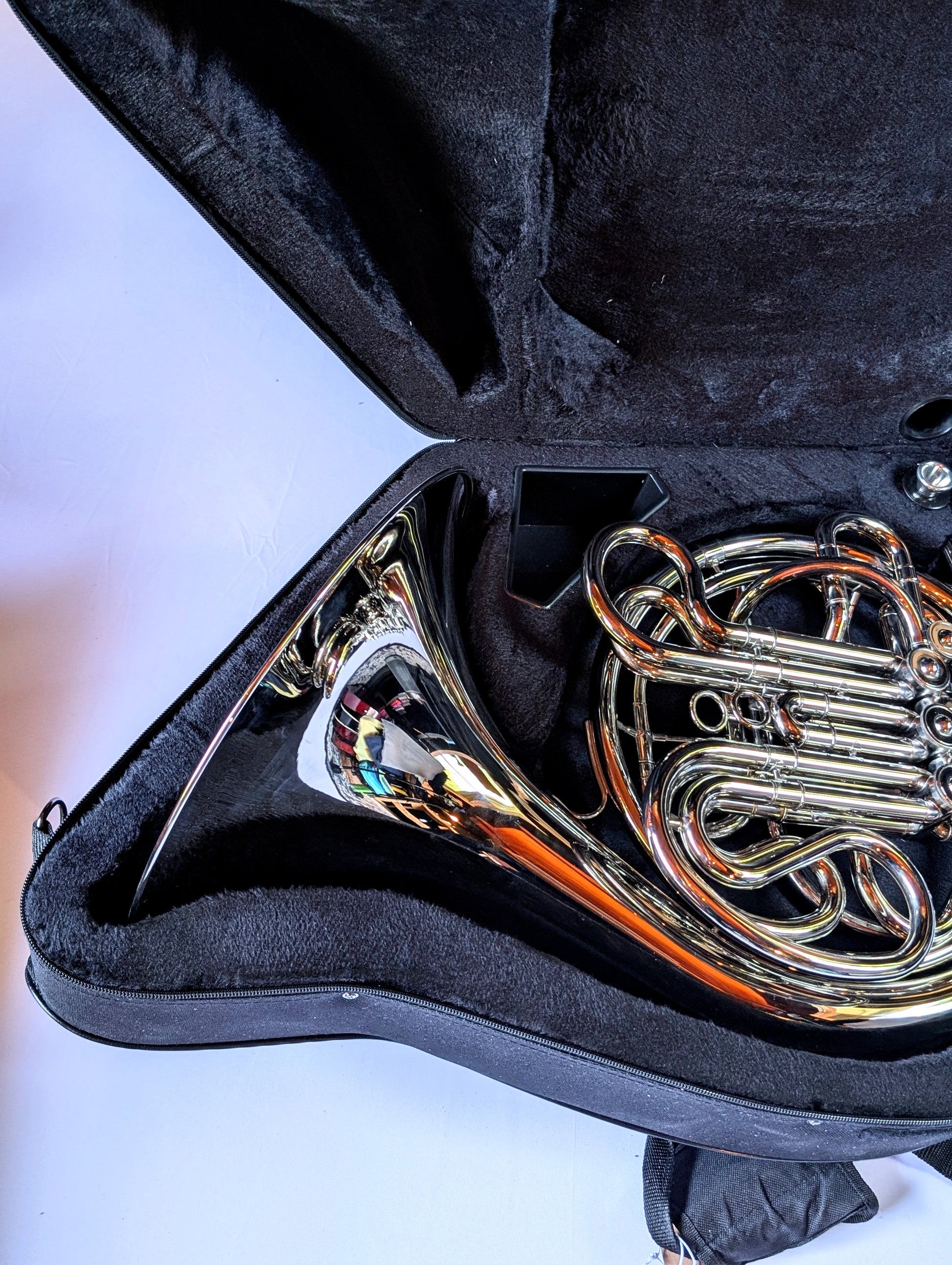 Silver-plated double French horn with F and Bb sides, thumb trigger mechanism, coiled tubing, and bell facing right