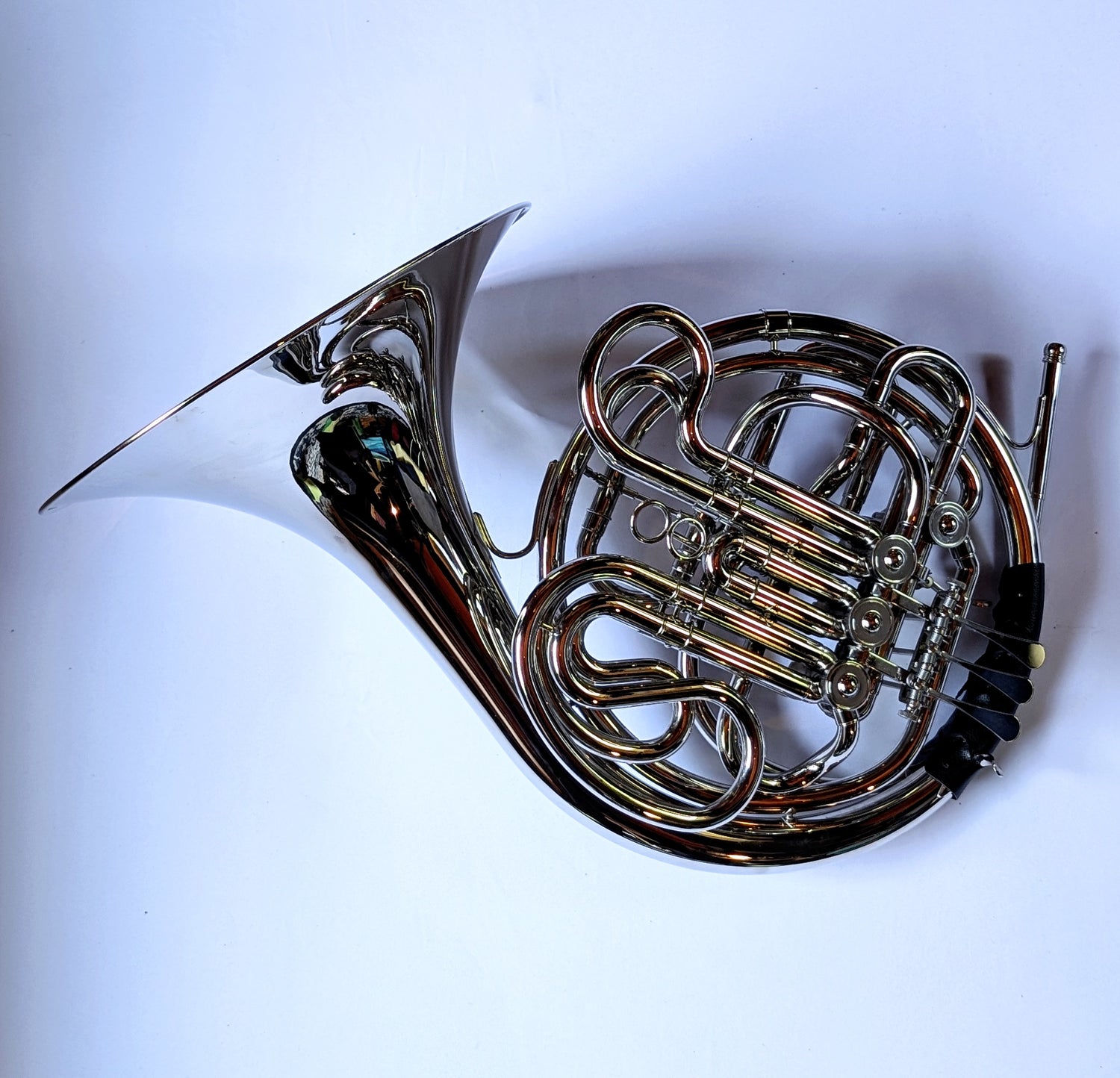 Silver-plated double French horn with F and Bb sides, thumb trigger mechanism, coiled tubing, and bell facing right